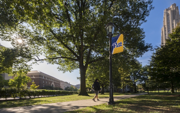 A view of campus including a blue and gold Pitt banner