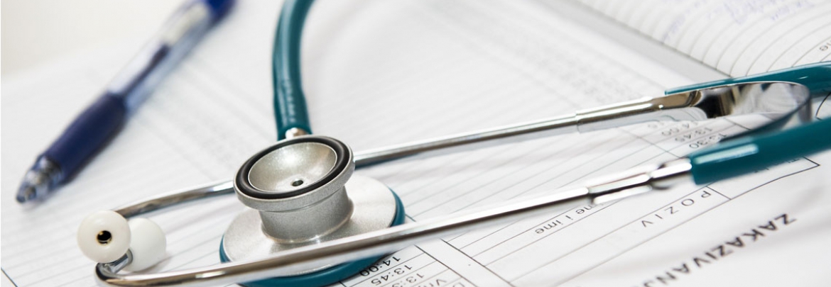 A stethoscope and pen sit atop a notebook. 